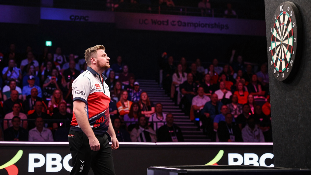 Professional darts player throwing at the oche in a packed arena