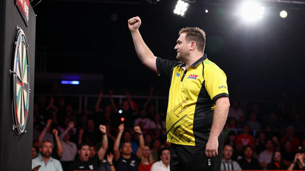 PDC darts player celebrating match victory with fist pump in arena with crowd cheering