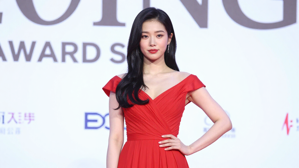 Young pop artist at an entertainment awards ceremony in elegant red dress